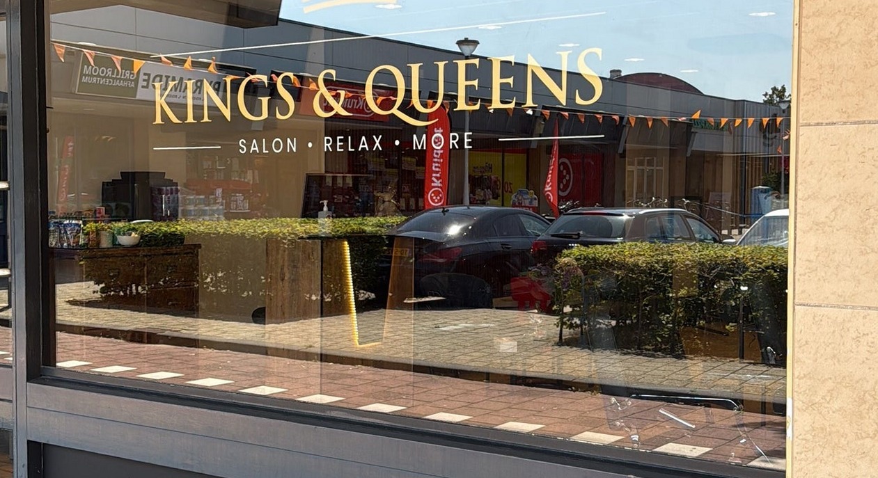 De gouden belettering Kings & Queens op het raam van de salon