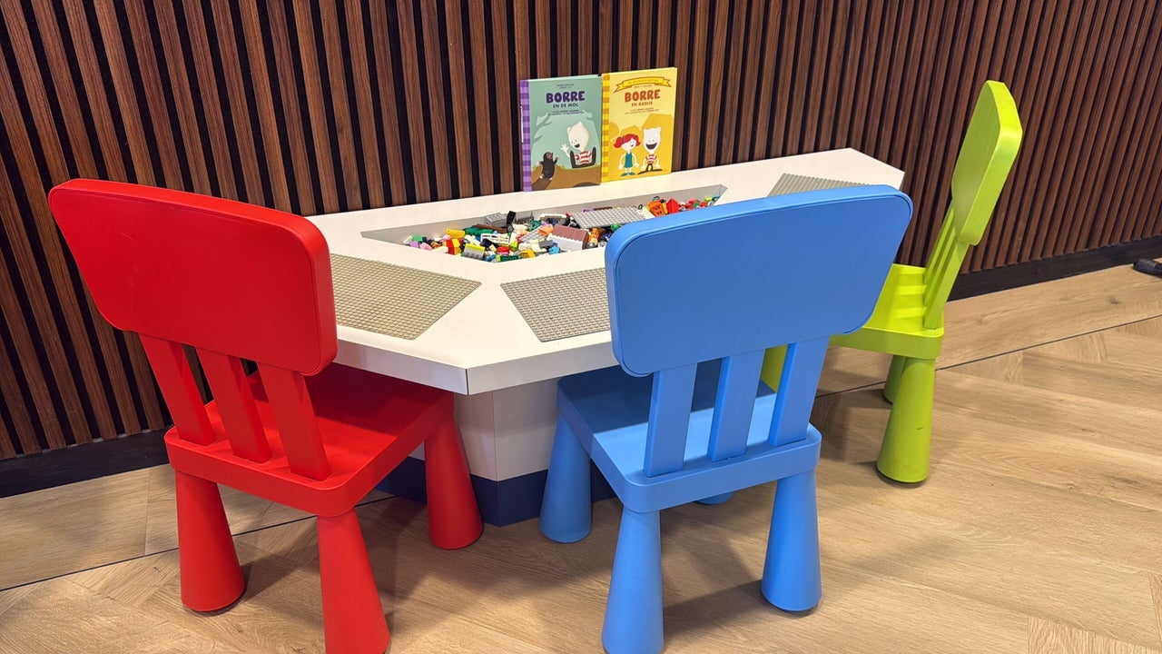 De speelhoek: een speeltafel met rode, blauwe en groene kinderstoeltjes