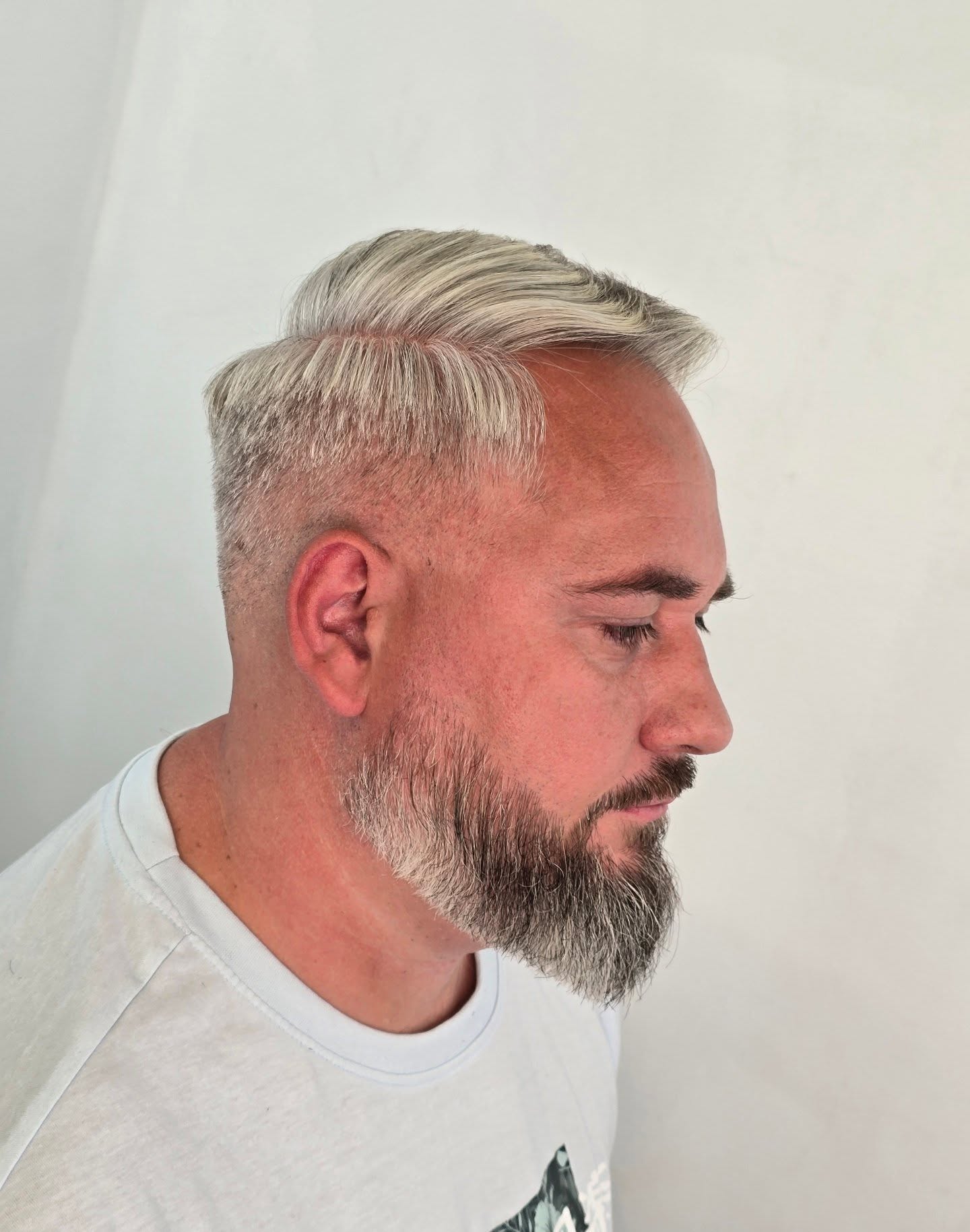 Herenkapsel: platinablonde bovenkant, kort opzij en een grijze baard, van opzij